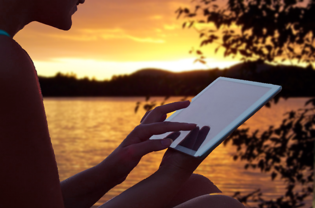 Sitting by lake working on a digital device.